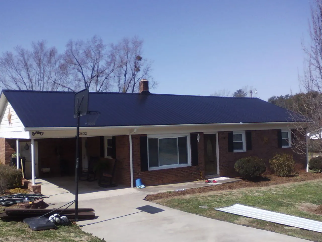 Finished dark blue metal roof on a brick ranch with a carport in Gordonsville