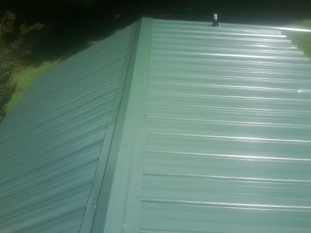 New green metal panels meeting at the ridge of a roof — Flat Roof Repair work by our crew in Gordonsville