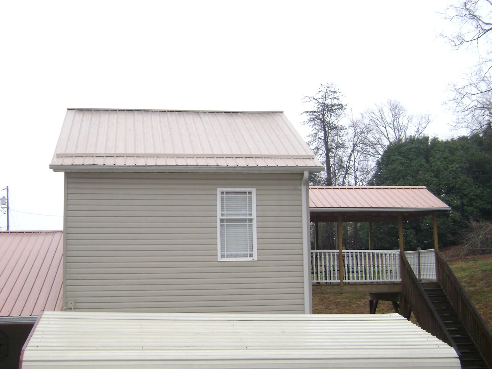 Tan metal roofs on a two story addition and attached porch, from a Roof Replacement job in Gordonsville