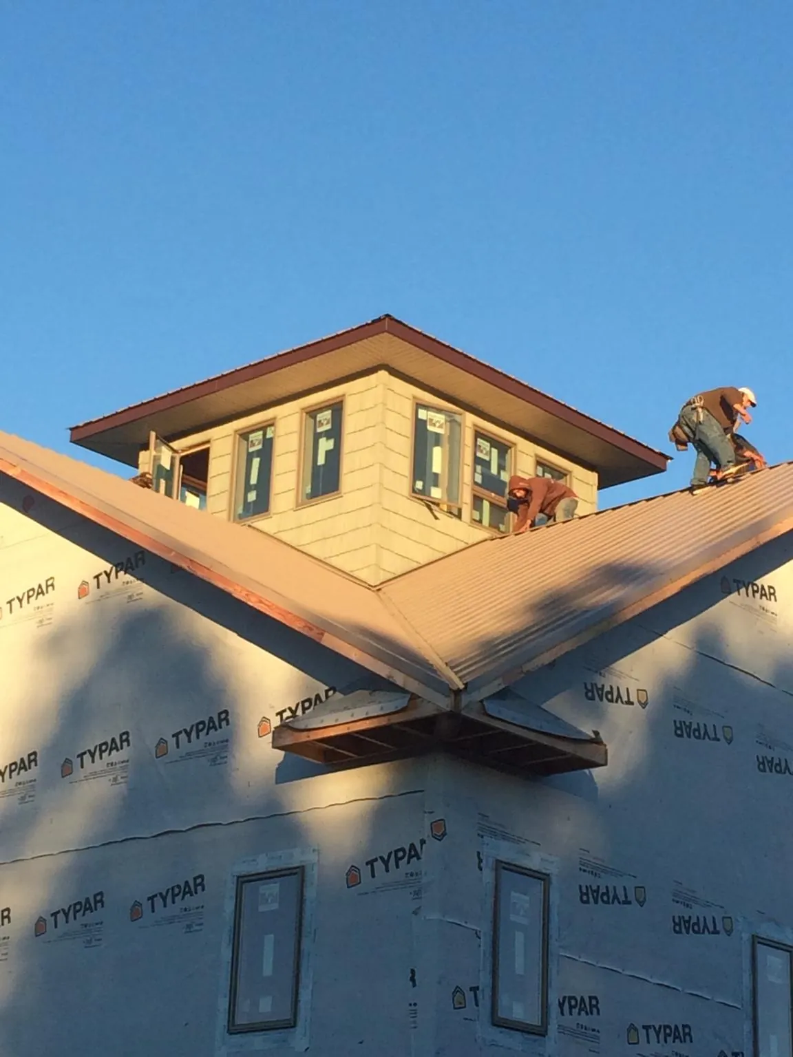 Roofers working around a rooftop cupola on a new metal roof at sunset — Roof Waterproofing in Gordonsville by Roofing Brothers